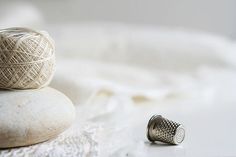 a ball of yarn sitting on top of a pile of rocks next to a spool of thread