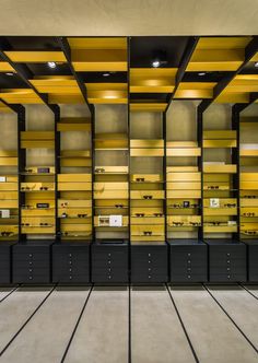 a room filled with lots of yellow and black shelves next to each other on top of cement flooring