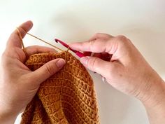 two hands are working on a piece of yarn that has been crocheted together