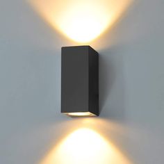 a black wall light with two lights on it's side and one is turned on