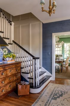 a living room with blue walls and wooden furniture in front of a staircase leading to the dining room