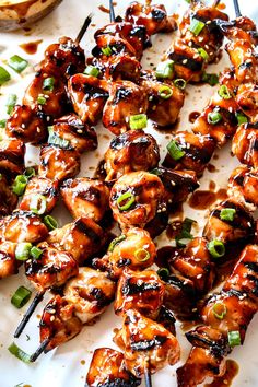 chicken skewers on a white plate with green onions