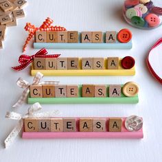 three wooden letters spelling out the word cuteasa on a table with ribbon and buttons