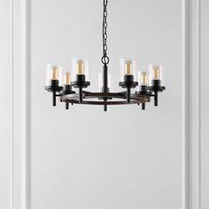 a chandelier with six lights hanging from it's center, in front of a white wall