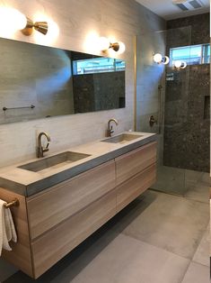 a bathroom with two sinks and a large mirror on the wall next to a walk in shower