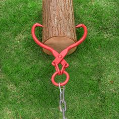 a log with chains attached to it sitting in the grass next to a pair of pliers