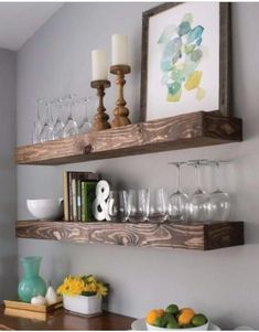 two wooden shelves with wine glasses and fruit on them in a dining room table area