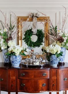 two blue and white vases sitting on top of a wooden table next to a mirror