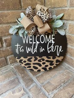 a welcome sign with leopard print and bows on the front of a brick wall that reads, welcome to wild in here