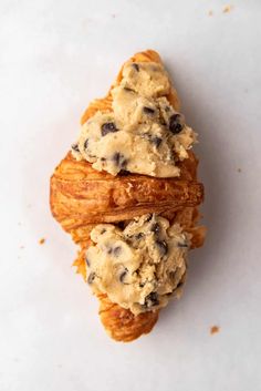 two croissants with ice cream and chocolate chips on them sitting on a white surface