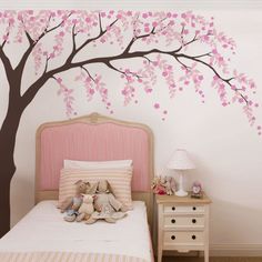 a bedroom with a tree painted on the wall and stuffed animals in front of it