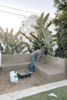 a man standing on top of a cement bench next to a planter filled with plants