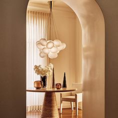 a dining room table with vases and lamps hanging from it's centerpiece