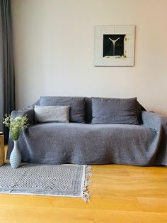 a living room with a couch and rug on the floor next to a painting hanging on the wall