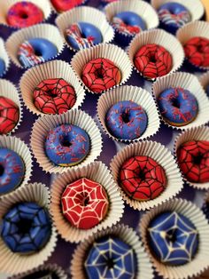 there are many cupcakes with sprinkles and spiderman decorations on them