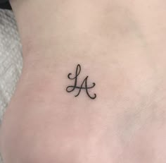 a small tattoo on the back of a woman's lower leg, with an initial