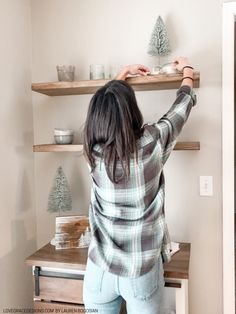 a woman standing in front of a wooden shelf holding a plate on top of it