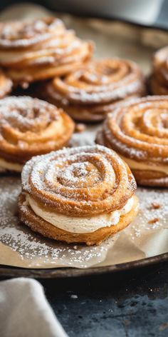 several pastries are sitting on a plate with powdered sugar and icing around them