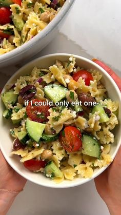 two bowls filled with pasta and veggies on top of a white table next to each other