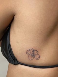 a woman's stomach with a small flower tattoo on the left side of her belly