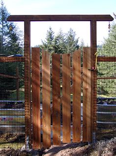 the gate is made out of wood and has a wire mesh fence around it,