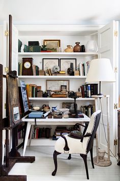 a room with a chair, desk and bookshelf full of various items in it