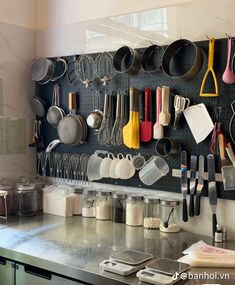 a kitchen counter with pots and pans hanging on the wall above it is an assortment of cooking utensils