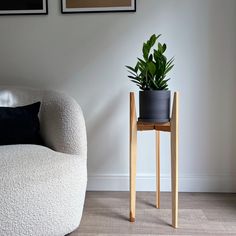 a white chair sitting next to a potted plant on top of a wooden table