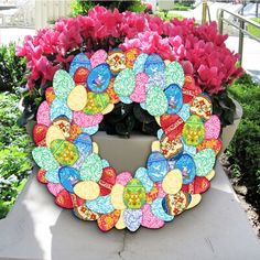 a wreath made out of buttons sitting on top of a cement slab next to pink flowers