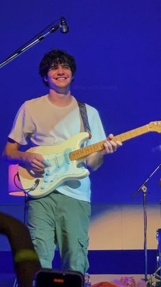 a young man playing an electric guitar on stage