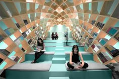 two women are sitting on the floor in a room with bookshelves and shelves