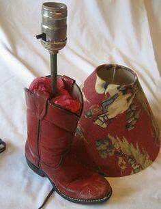 a pair of red cowboy boots sitting next to a lamp on a white cloth background