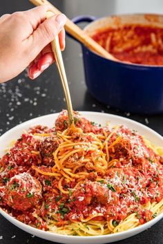 someone is eating spaghetti with meatballs and sauce