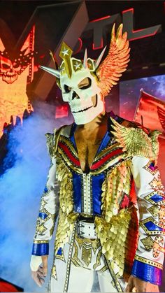 a man wearing a mask with wings on top of his head in front of a stage