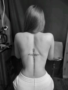 a woman's back with a cross tattoo on her lower back and the upper part of her body