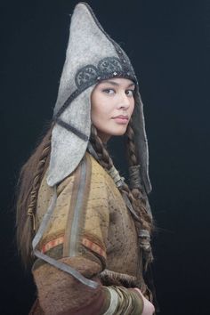 a woman with braids and a hat on her head is standing in front of a black background