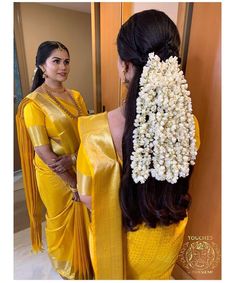 a woman with long hair wearing a yellow sari and white flowers in her hair