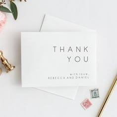 a thank you card sitting on top of a desk next to a pen and flowers