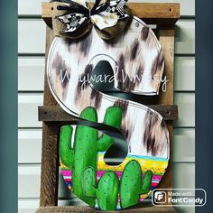 a wooden sign with a green cactus on it and a bow hanging from the front