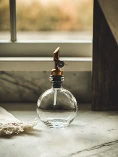 a glass bottle with a wooden top sitting next to a window