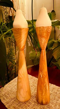 two wooden candlesticks sitting next to each other on top of a table cloth