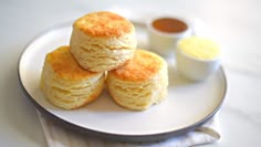 three biscuits sitting on top of a white plate next to a cup and saucer