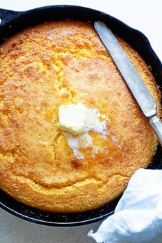 a skillet with some bread and butter in it next to a knife and fork