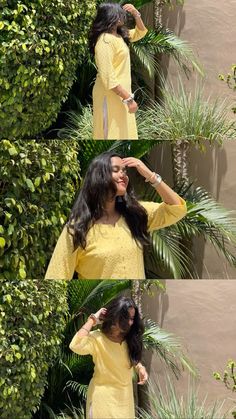 a woman in yellow dress standing next to plants and looking into the distance with her hand on her head