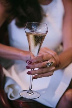 a close up of a person holding a wine glass with a ring on it's finger