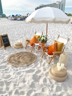 chairs and an umbrella are set up on the sand at the beach for a picnic