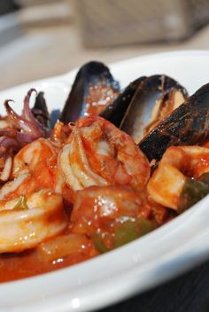 a white bowl filled with seafood and mussels