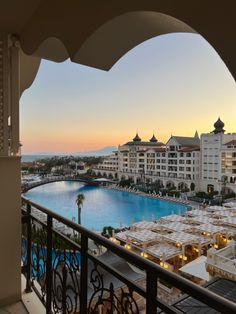 an outdoor swimming pool next to the ocean at sunset or dawn with buildings in the background