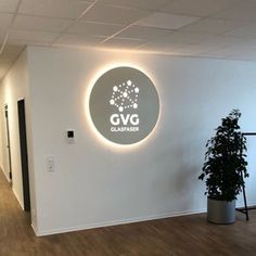 an office with white walls and wood flooring has a circular logo on the wall