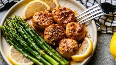 chicken and asparagus on a plate with lemon wedges